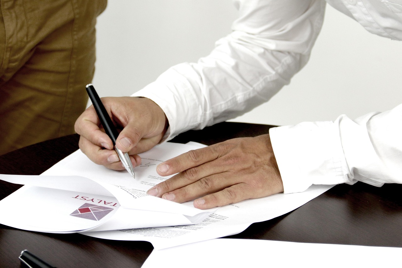 A smiling car owner holding insurance documents next to a shiny new bumper